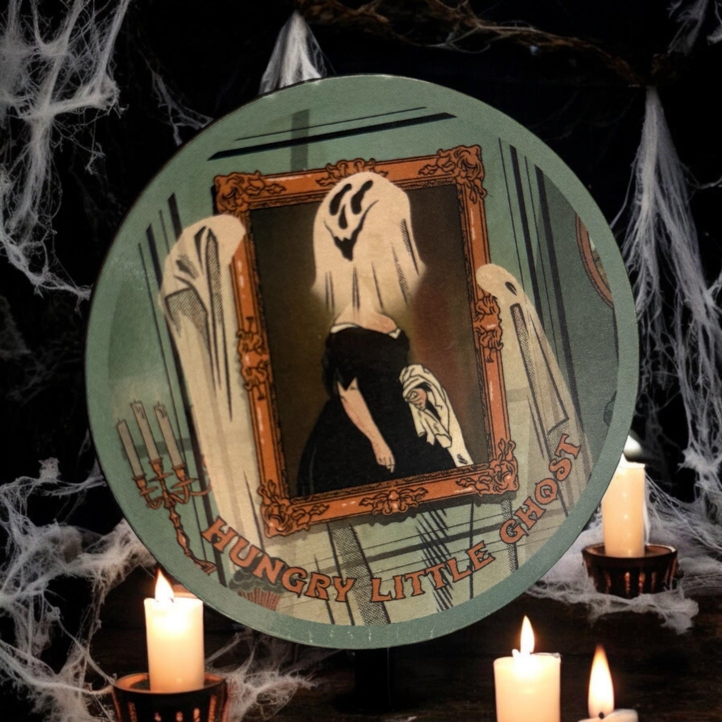 A round magnet with a ghost theme, featuring a stylized ghost in a frame, set against a dark background with lit candles.